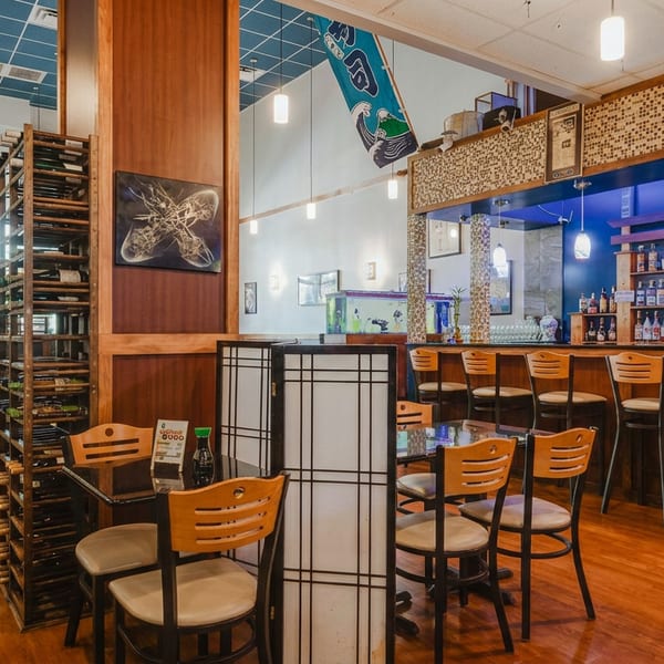Inviting restaurant interior with wooden tables, chairs, a well-stocked bar, and traditional Japanese decor.